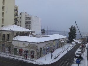 Θέα προς την παραλία, με χιονισμένες τις σκεπές και τα πεζοδρόμια 