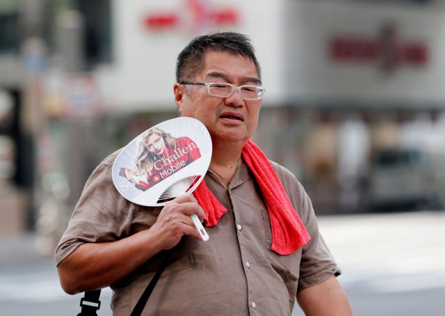 A man uses a fan as he walks on a street in Tokyo