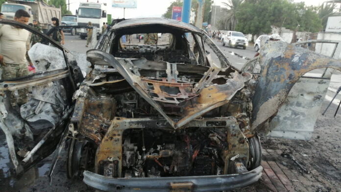 Security man inspects the wreckage of a car at the site of an explosion that killed a journalist in Aden, Yemen