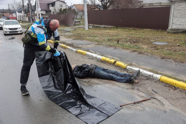 A volunteer opens a body bag to collect the body of a civilian, who according to residents was killed by Russian soldiers, in Bucha